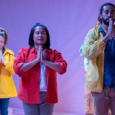 3 characters with hands in prayer position. The American Dream 2.0 Photo by Anthony Lee