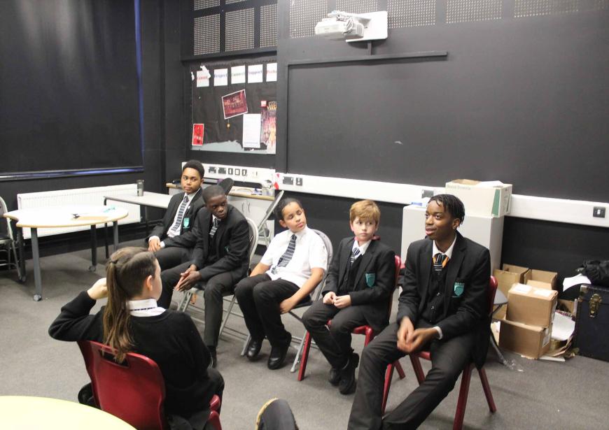 5 pupils in school uniform in black wall theatre room, engaging in a group activity