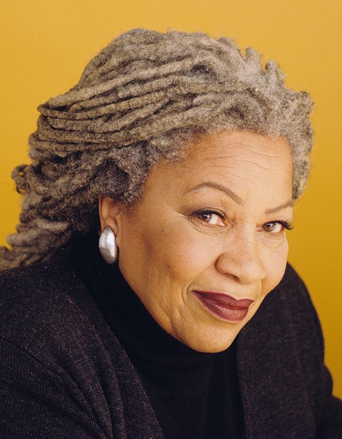 A colour photo of a smiling Toni Morrison against a yellow background